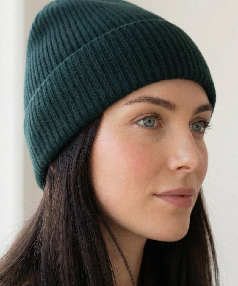 Woman wearing dark green ribbed cashmere hat indoors, front view
